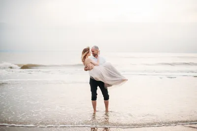 Фотография пары, стоящей на берегу моря · Бесплатные стоковые фото