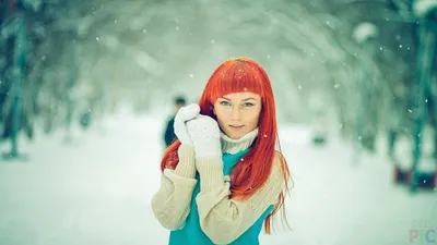 Рыжая девушка смотрит на заснеженный лес