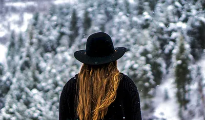 Девушка с длинными волосами стоит спиной в городе с букетом еловых веток  снежная зима | Премиум Фото