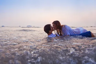 Счастливая молодая влюбленная пара на фоне моря гуляет по пляжу на фоне  голубого неба и веселится летним днем. | Премиум Фото